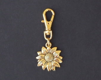 May include: A gold-colored sunflower keychain with a metal clasp.