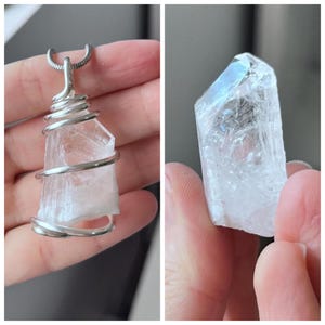 May include: A clear crystal pendant wrapped in silver wire, hanging from a silver chain. The crystal is a natural, raw, and unpolished shape.