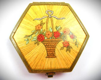 Polvos compactos pequeños con diseño floral, firmados por Houbigant.