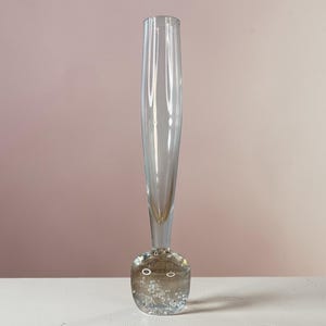 May include: A white ceramic mug with a black handle and the text "But First, Coffee" in a black, handwritten-style font. The mug is on a white surface.