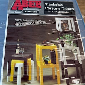 May include: Stackable Parsons Tables in various colors, including black, yellow, and white. The tables are shown in different arrangements, with a size of 14" x 14" x 14" high when assembled. The image also includes text that says "ABEE Lifestyles".