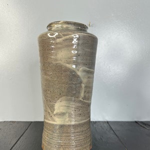 May include: A gray ceramic vase with a white swirl design. The vase has a rounded bottom and a slightly flared opening.