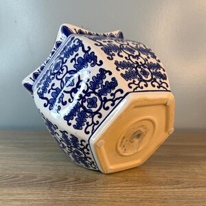 Puede incluir: Una maceta de cer&aacute;mica blanca y azul con base hexagonal y un patr&oacute;n floral decorativo. La maceta tiene una forma &uacute;nica con bordes puntiagudos y un dise&ntilde;o detallado, perfecta para a&ntilde;adir un toque de elegancia a cualquier espacio.