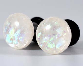 May include: Pair of white iridescent ear gauges with black rubber backing.