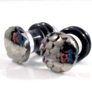 Może przedstawiać: Para srebrnych i czarnych rozpychaczy do uszu z wzorem łusek. Rozpychacze są wykonane z akrylu i metalu.