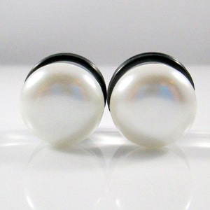 May include: A pair of pearl earrings with a black metal setting. The pearls are white and round.