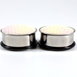 May include: A pair of stainless steel ear gauges with a white and pink patterned design. The gauges are 0g in size.