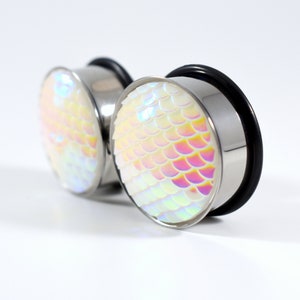 May include: A pair of iridescent white ear gauges with a mermaid scale design. The gauges are made of stainless steel and have a black o-ring.