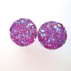 May include: A pair of iridescent pink stud earrings with a sparkly, textured finish.