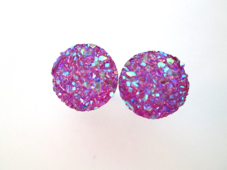 May include: A pair of iridescent pink stud earrings with a sparkly, textured finish.