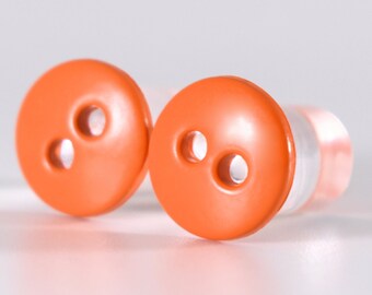 May include: Two orange plastic buttons with two holes each. The buttons are round and have a glossy finish.