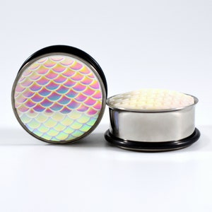 May include: A pair of iridescent mermaid scale ear gauges. The gauges are made of stainless steel and have a black o-ring. The scales are a rainbow of colors, including pink, blue, green, and yellow.