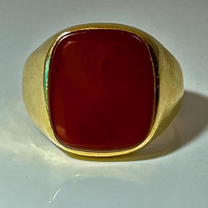 May include: A gold ring with a large, square, red carnelian gemstone.