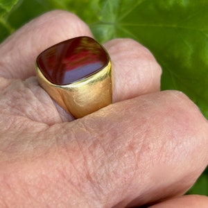 May include: A gold ring with a square, red carnelian gemstone.