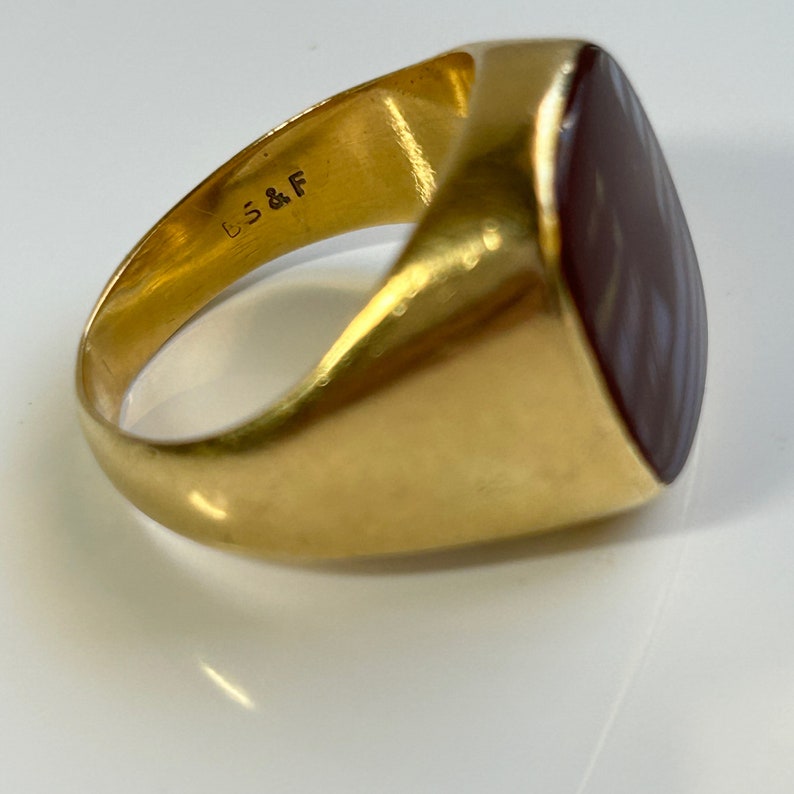May include: A gold signet ring with a brown and white agate stone. The ring is marked "B.S.& F."