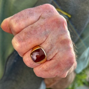 May include: A gold ring with a red and white carnelian stone.