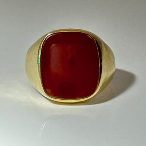 May include: A gold ring with a large, red carnelian gemstone.