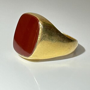 May include: A gold signet ring with a red carnelian stone.