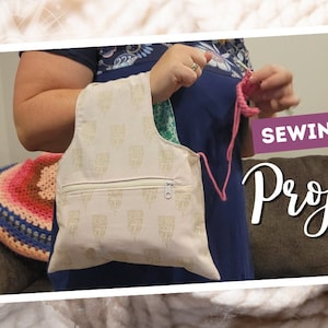 May include: A white project bag with a zippered pocket and a gold pattern. The bag is being held by a person who is knitting with pink yarn. The text "Sewing Tutorial Project Bag" is in the upper right corner of the image.