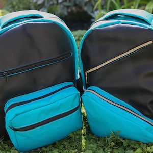 May include: Two black and turquoise backpacks with zippered pockets. The backpacks have a mesh pocket on the side.