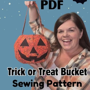 May include: An orange pumpkin-shaped Trick or Treat bucket with a black face design and a spiderweb pattern. The bucket has a handle and the text "Trick or Treat Bucket Sewing Pattern" is displayed.