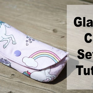 May include: A pink fabric glasses case with a unicorn and rainbow design. The case has a button closure and the text "Glasses Case Sewing Tutorial" is visible in the background.