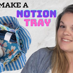 May include: A blue and white striped fabric tray with a floral pattern inside. The tray is filled with sewing notions, including thread, ribbon, and a measuring tape. The text "LETS MAKE A NOTION TRAY" is visible at the top of the image.