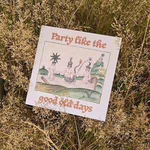 May include: A square print featuring the text Party like the good old days in a terracotta font. The illustration depicts three figures in a body of water, one with a mermaid tail, surrounded by celestial symbols, a sun, and a moon.