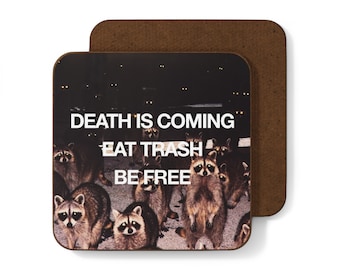 Puede incluir: Un posavasos marrón con una imagen en blanco y negro de mapaches con ojos brillantes. El texto "DEATH IS COMING EAT TRASH BE FREE" está impreso en blanco en el posavasos.