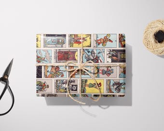 Puede incluir: Un regalo envuelto con ilustraciones de cartas del tarot, atado con hilo. El regalo es rectangular y presenta imágenes coloridas de una baraja de tarot. Un carrete de hilo y unas tijeras negras están junto al regalo sobre una superficie blanca.