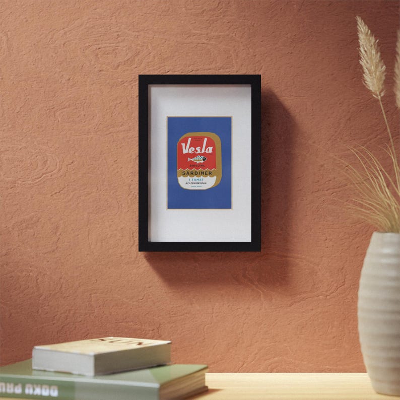Puede incluir: Una impresi&oacute;n enmarcada de una etiqueta vintage de una lata de sardinas. La etiqueta es roja y dorada con el texto "Vesla Sardiner i Tomat" y un dibujo de una sardina.