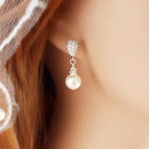 May include: Silver dangle earrings with a small pearl drop and a crystal-encrusted top.