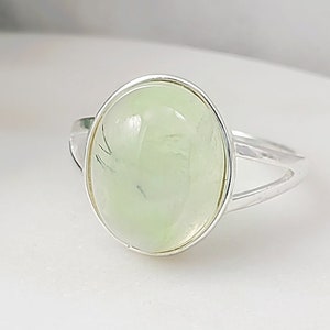 This silver prehnite ring is made with a 12x15mm oval, pale green, genuine prehnite gemstone cabochon which we set in a 925 Sterling silver ring bezel. This US size 5.75 or 8.25 green ring makes a great August birthstone jewelry gift for her.