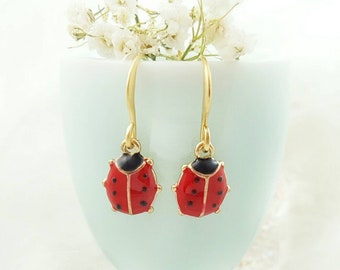 May include: A pair of gold earrings with red and black ladybug charms.