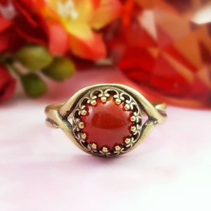 May include: A gold ring with a red gemstone set in a decorative filigree design.