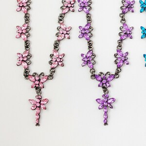Puede incluir: Cuatro collares con dijes de mariposa y aretes a juego. Los collares son plateados con mariposas de cristal rosa, morado, azul y verde. Los aretes son plateados con mariposas de cristal a juego.