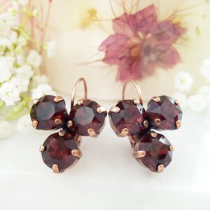 May include: A pair of copper earrings with three dark red crystal stones on each earring.