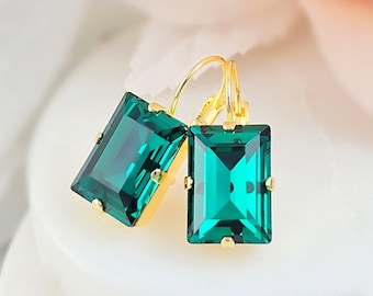May include: A pair of gold earrings with emerald green rectangular shaped stones.