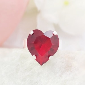 May include: A heart-shaped ring with a bright red gemstone.