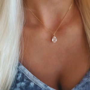 Puede incluir: Un collar de cadena dorada con un colgante de cristal transparente en forma de l&aacute;grima.