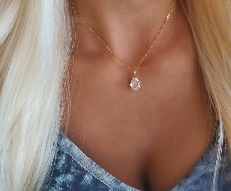 Puede incluir: Un collar de cadena dorada con un colgante de cristal transparente en forma de l&aacute;grima.