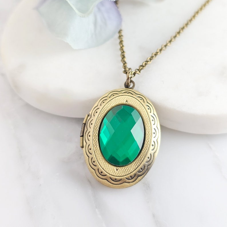 Puede incluir: Un collar con un medall&oacute;n ovalado de oro adornado con una piedra preciosa verde. El medall&oacute;n tiene un dise&ntilde;o detallado alrededor del borde.