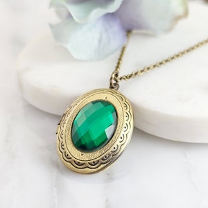 Puede incluir: Un collar de oro con un colgante de medall&oacute;n con una piedra preciosa verde. El medall&oacute;n tiene un dise&ntilde;o ornamentado detallado alrededor del borde.
