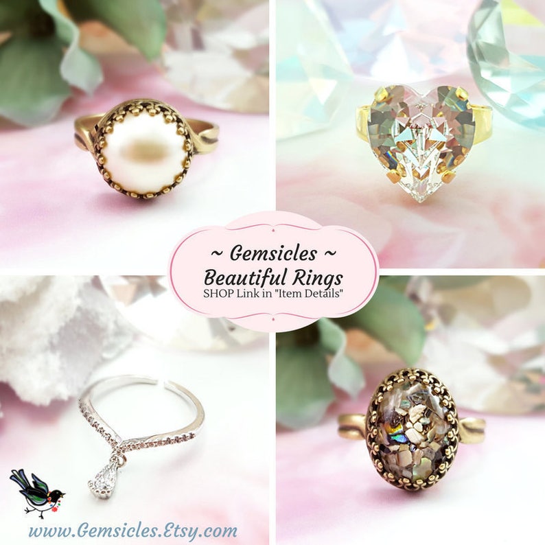 May include: Four different rings with various gemstones. The first ring has a white pearl in a gold setting. The second ring has a clear heart-shaped gemstone in a gold setting. The third ring has a clear teardrop-shaped gemstone hanging from a silver band. The fourth ring has a multi-colored gemstone in a gold setting.  ~Gemsicles~ Beautiful Rings SHOP Link in "Item Details"