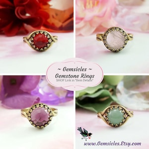 May include: Four gemstone rings with ornate gold settings. The rings feature red, pink, purple, and green gemstones.