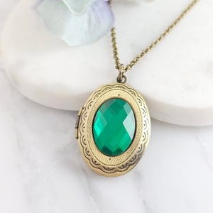 Puede incluir: Un collar con un medall&oacute;n de oro adornado con una piedra preciosa verde de forma ovalada. El medall&oacute;n tiene un dise&ntilde;o ornamentado detallado alrededor del borde.