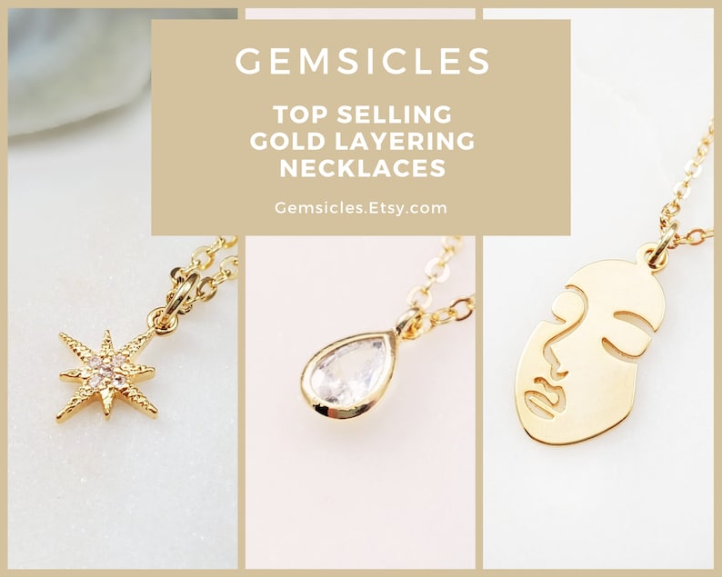 May include: Three gold necklaces with different pendants: a starburst with clear stones, a teardrop-shaped clear stone, and a face outline. The text "GEMSICLES TOP SELLING GOLD LAYERING NECKLACES Gemsicles.Etsy.com" is displayed above the necklaces.
