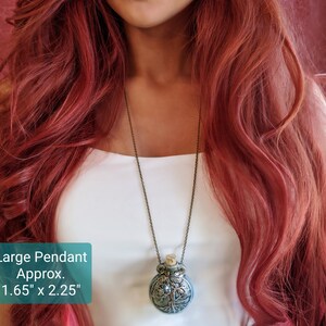 May include: A large pendant necklace with a detailed tree of life design. The pendant is approximately 1.65 inches wide and 2.25 inches tall, with a cork stopper. The chain is a dark bronze color.