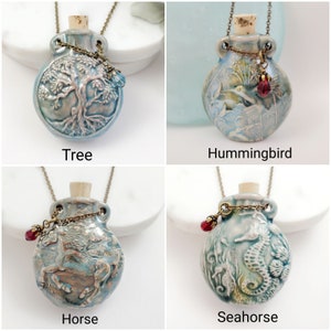 May include: Four ceramic pendant necklaces with different designs: a tree, a hummingbird, a horse, and a seahorse. Each pendant is a light blue bottle shape with a cork stopper, a bronze chain, and a decorative charm. The text labels each pendant.