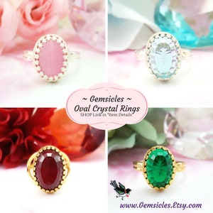 Puede incluir: Cuatro anillos de cristal ovalados con piedras de diferentes colores. Los anillos est&aacute;n engastados en monturas de plata y oro. Las piedras son rosa, azul, roja y verde. El texto "~ Gemsicles ~ Oval Crystal Rings SHOP Link in "Item Details"" se muestra sobre un fondo rosa.